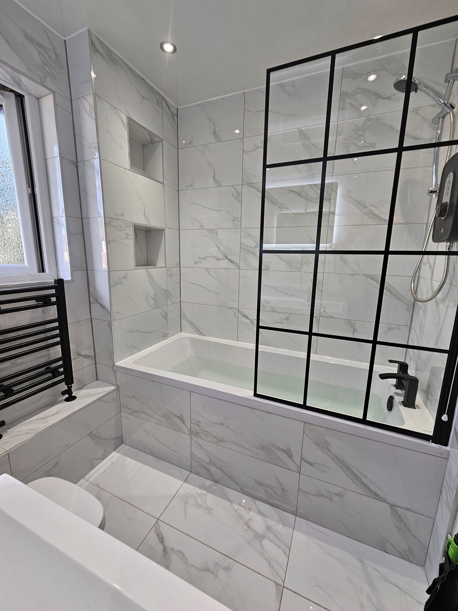 Marble bathroom with bath and black grid screen